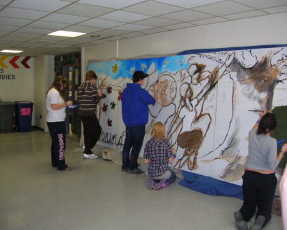 Students working on exterior mural directed by a visiting artist
